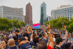 Eine große Menschenmenge beim Potsdamer Platz in Berlin. Viele schwenken Regenbogenfahnen.