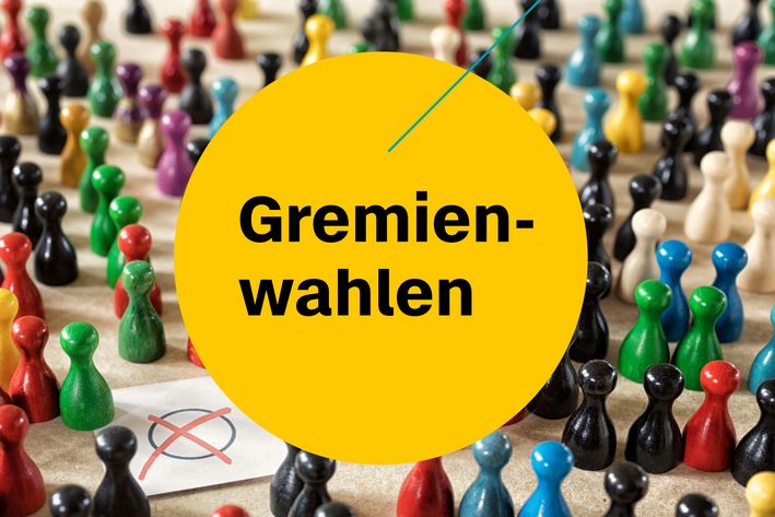 Spielfiguren in verschiedenen Farben stehen um ein Wahlkreuz herum