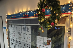 Adventskalender mit 24 Türchen in einer Glasvitrine, die weihnachtlich geschmückt ist.