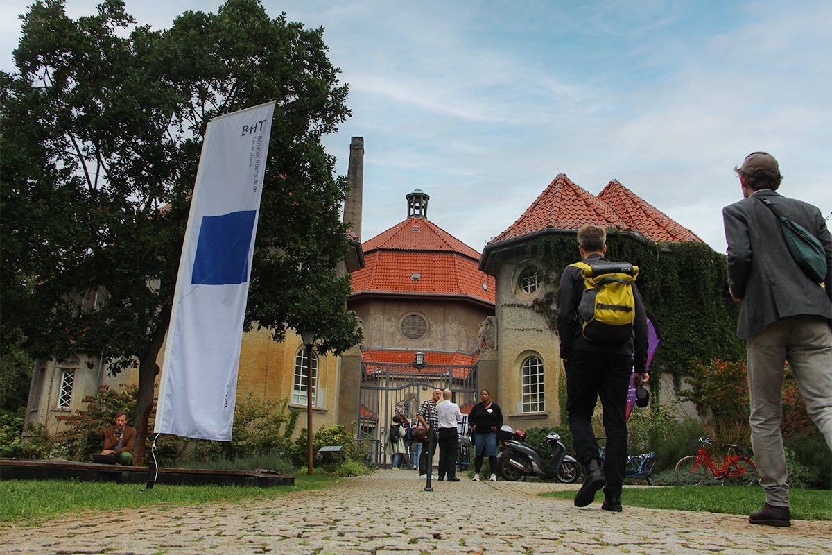 Menschen gehen zu einem Altbau-Kuppelgebäude.