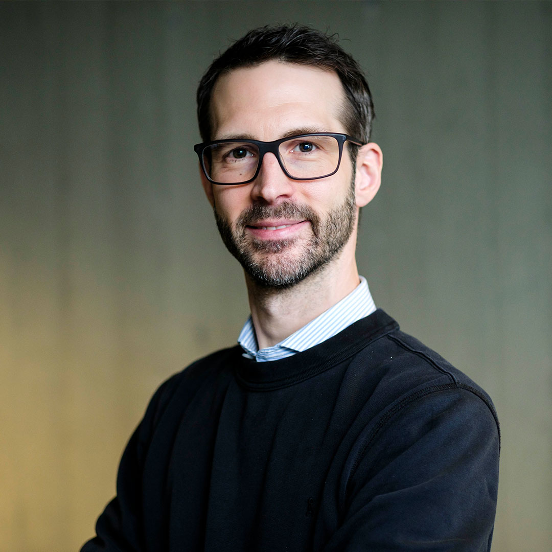 Portraitbild eines jungen Mannes mit Brille.